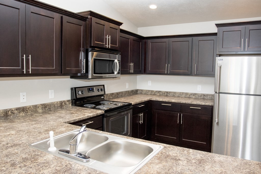 a kitchen with dark cabinets and stainless steel appliances