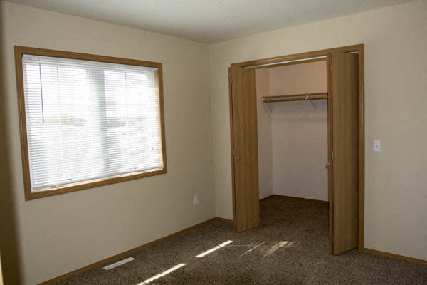 an empty bedroom with a window and a closet