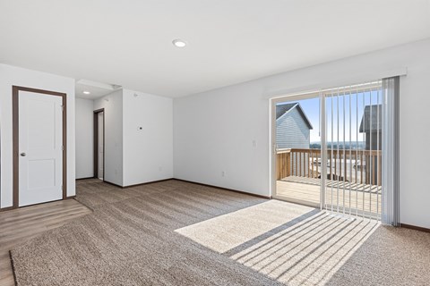 a living room with a door to a balcony and a carpeted floor