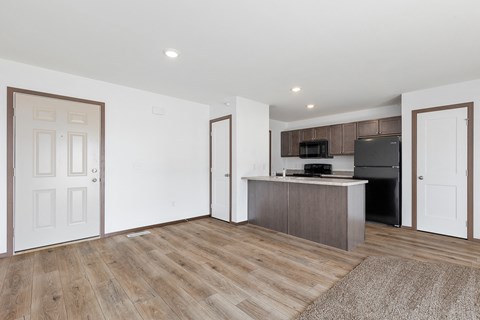an empty living room and kitchen with a refrigerator and a sink