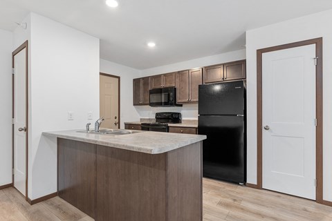 a kitchen with an island and a black refrigerator