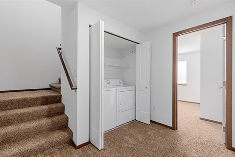 a room with stairs and a laundry room with a washer and dryer