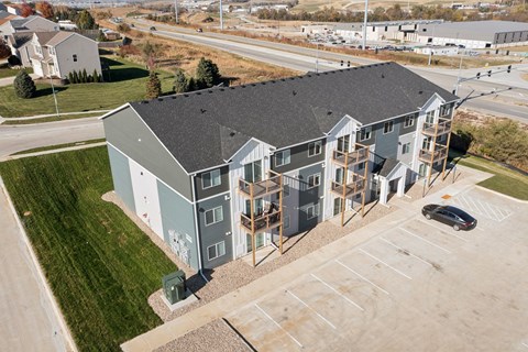 A modern apartment building with a parking lot in front.