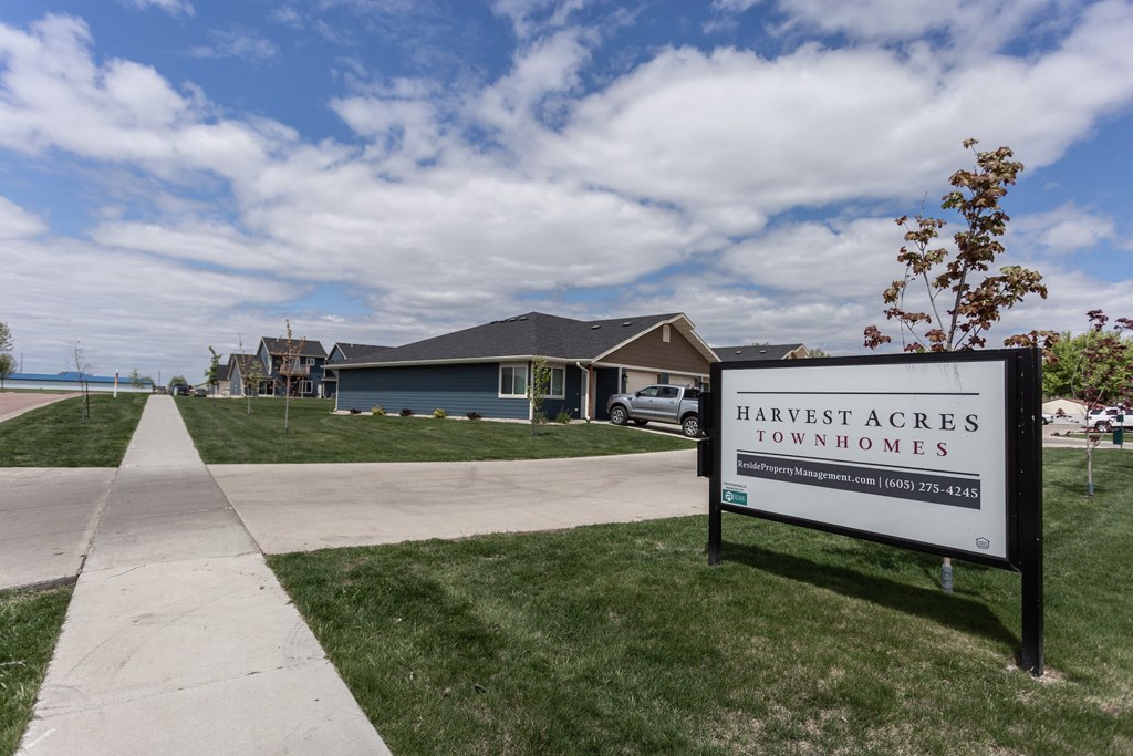 a sign that reads harvest acres townhomes in front of a house