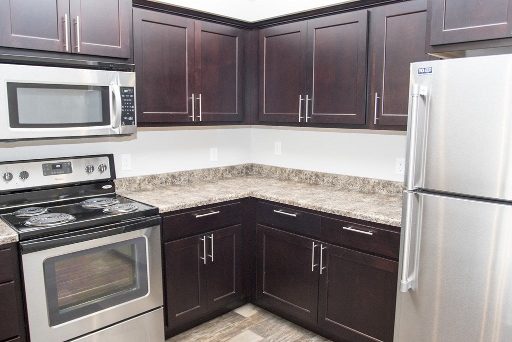 a kitchen with dark wood cabinets and stainless steel appliances