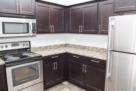 a kitchen with dark wood cabinets and stainless steel appliances