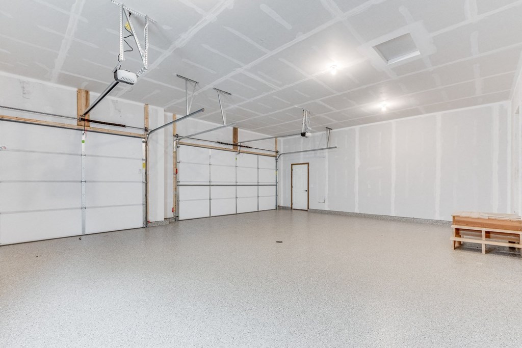 an empty garage with white walls and doors and a bench
