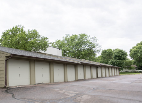 a row of garages in a parking lot with trees