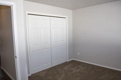 a bedroom with two closets and a carpeted floor