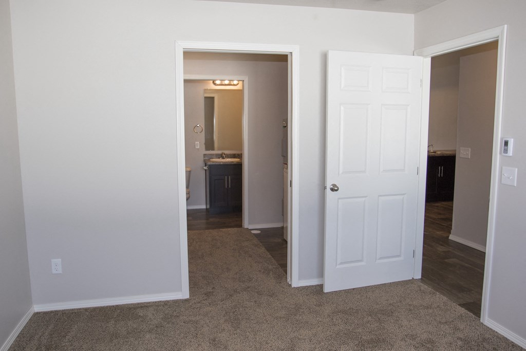 a bedroom with a door open to a hallway and a bathroom