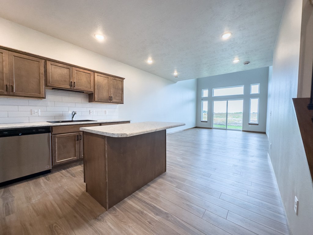 an empty kitchen and living room with wood flooring and a window