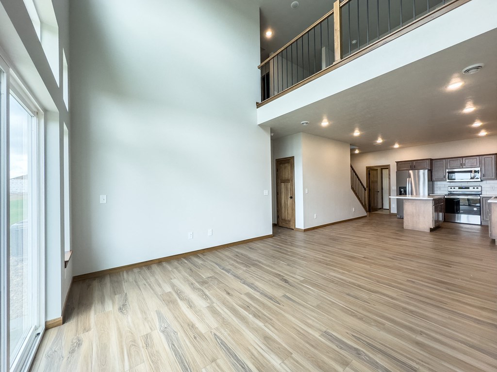the living room and kitchen of a new home with white walls and wood flooring