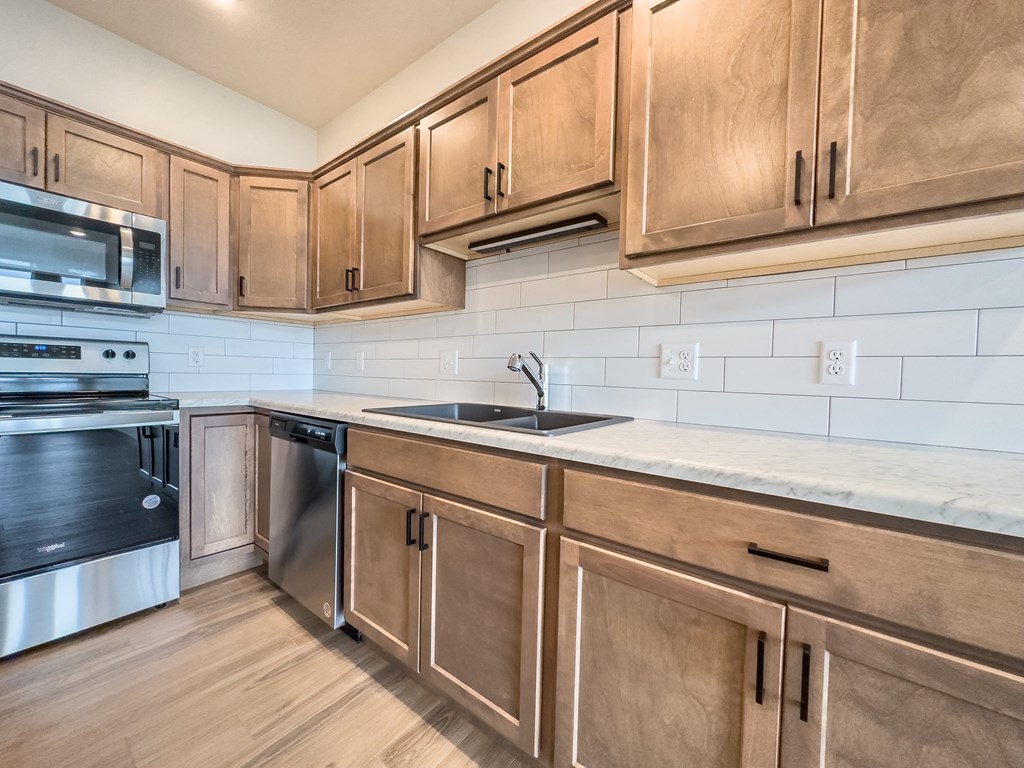 an empty kitchen with wooden cabinets and stainless steel appliances