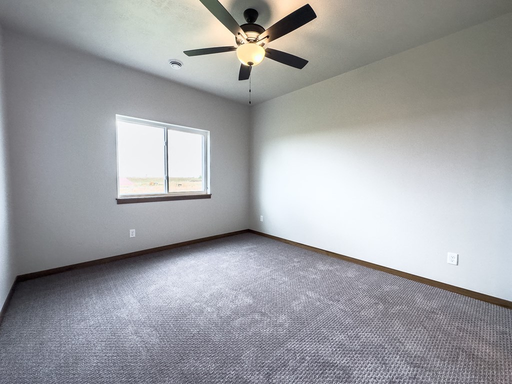an empty room with a ceiling fan and a window