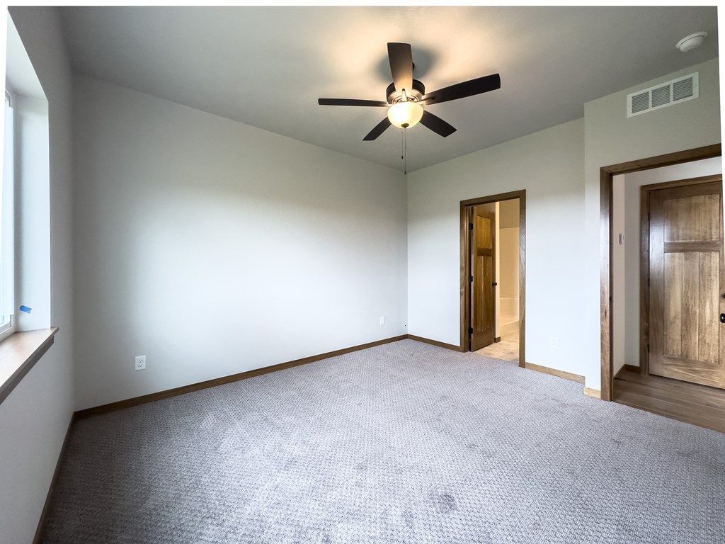 an empty living room with a ceiling fan