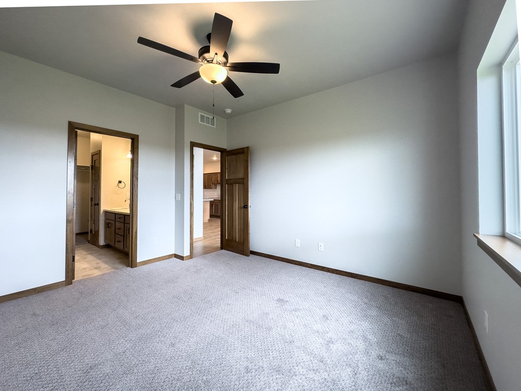 an empty living room with a ceiling fan