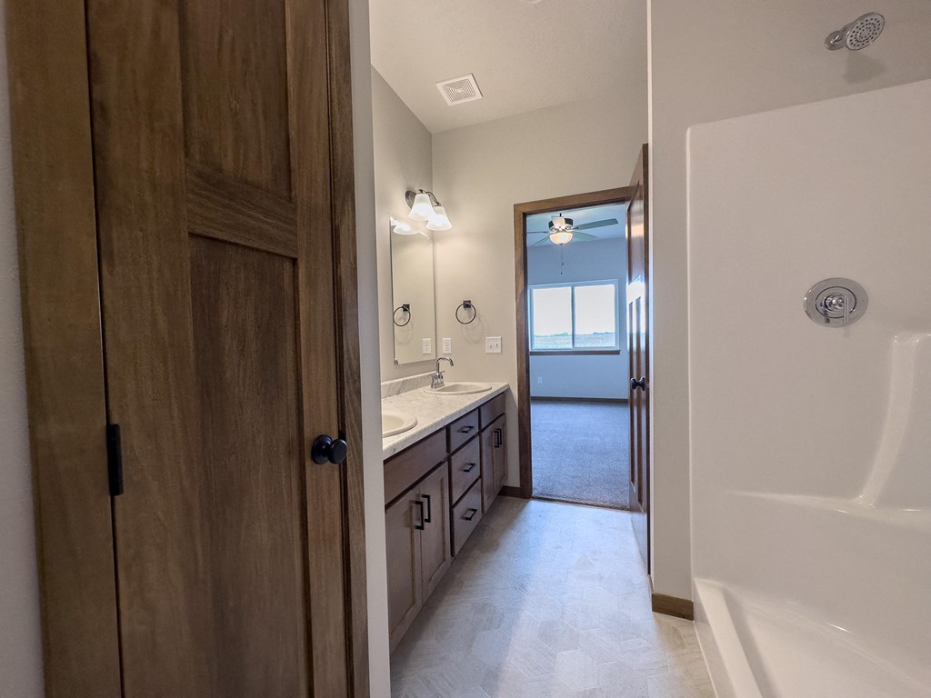 the view of a bathroom with a shower and a sink and a mirror