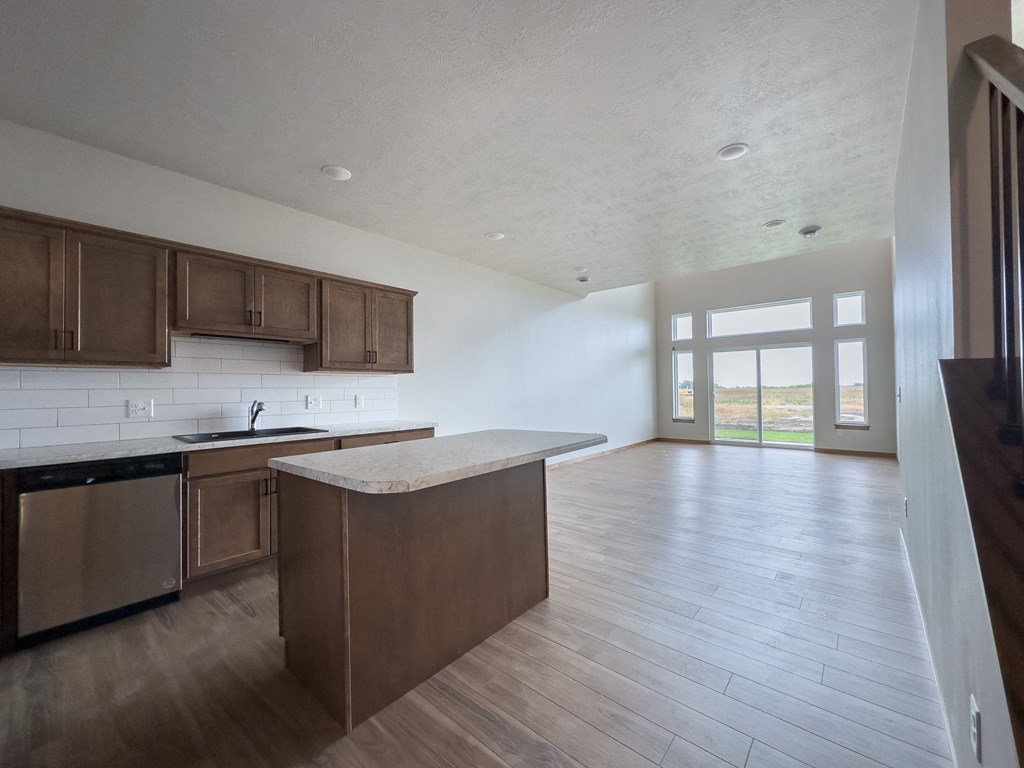 an empty kitchen and living room with wood flooring and a window