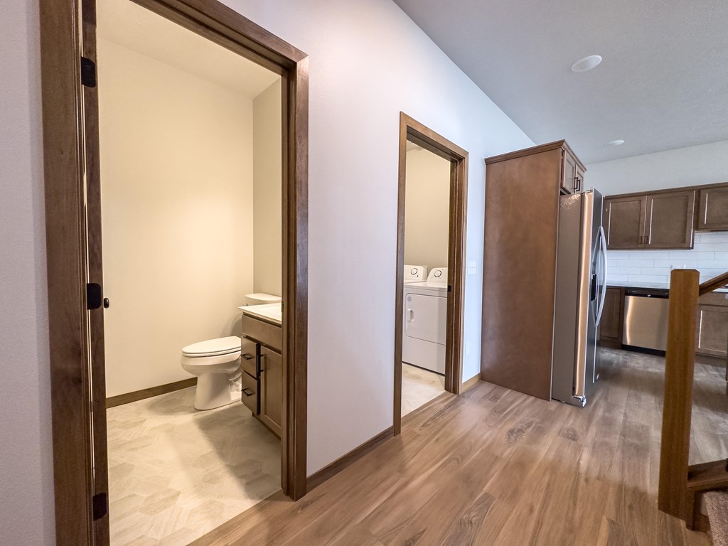a view of a bathroom and a hallway with a toilet and a refrigerator
