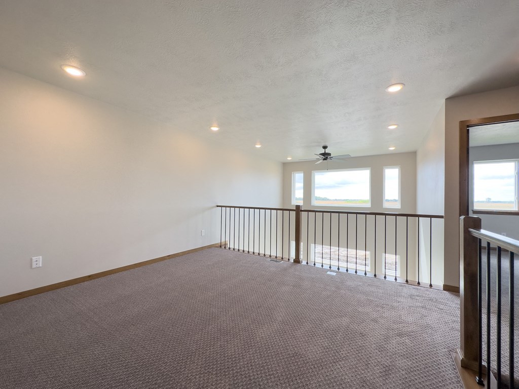 the upstairs living room with a railing and a window