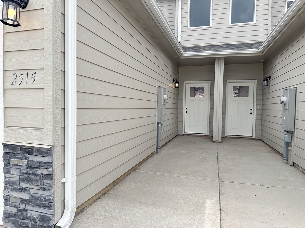a long hallway with two doors and a porch