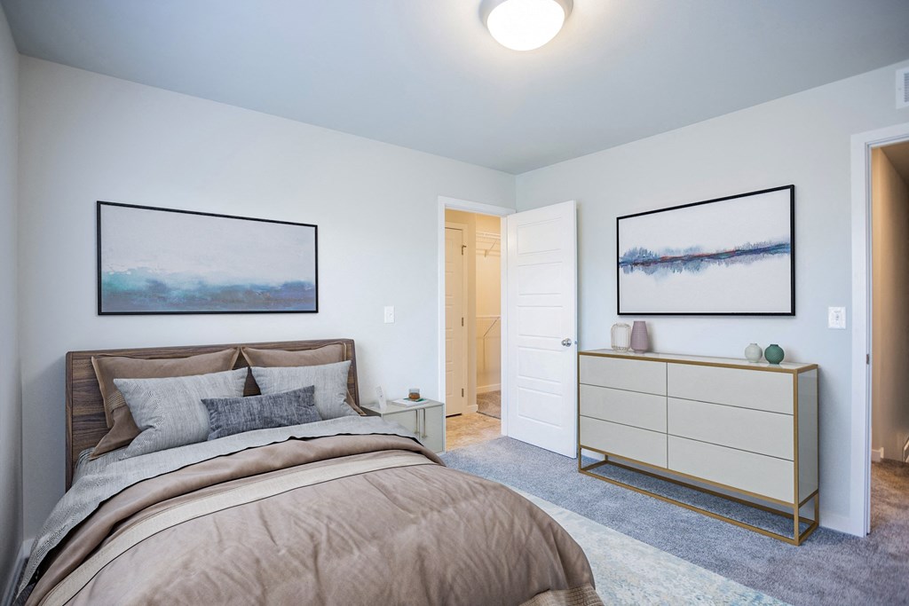a bedroom with a bed and a dresser with two paintings on the wall