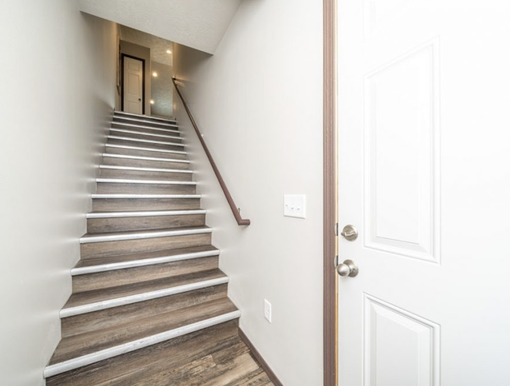 a staircase in a home with white walls and a white door