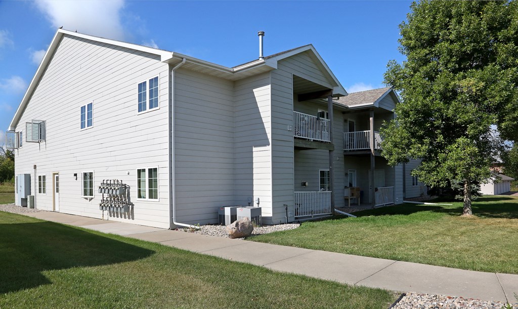 the exterior of a white house with a lawn and trees