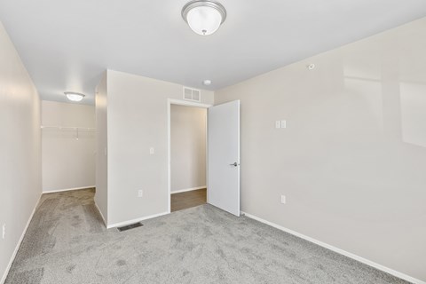 an empty living room with white walls and a door to a closet