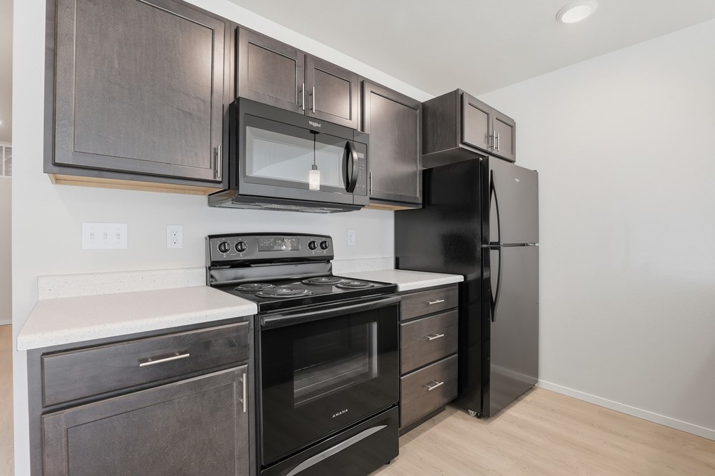 A kitchen with black appliances and wooden cabinets.