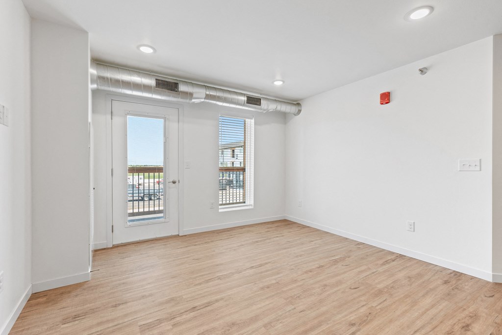 the living room of an apartment with white walls and wood flooring