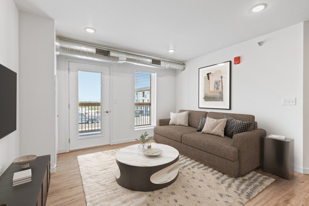 A living room with a brown couch, a coffee table, and a painting on the wall.