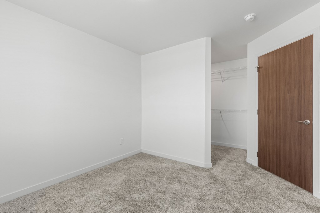 an empty room with white walls and a door to a closet