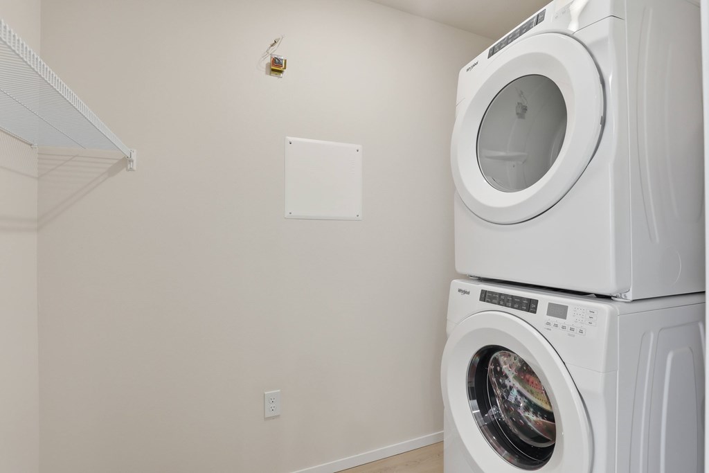 A white dryer is stacked on top of a white washing machine.