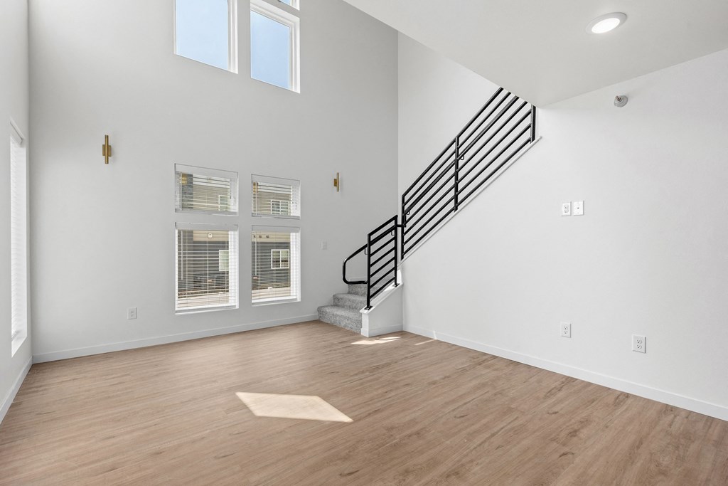 an empty living room with white walls and wood flooring and a staircase