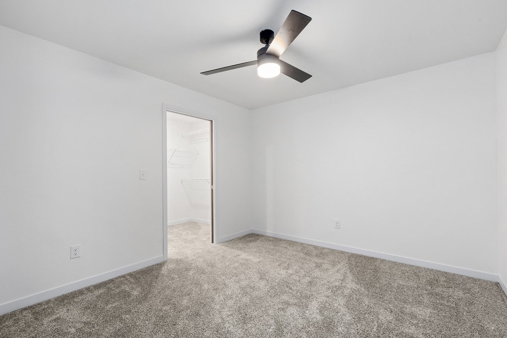 an empty room with carpet and a ceiling fan
