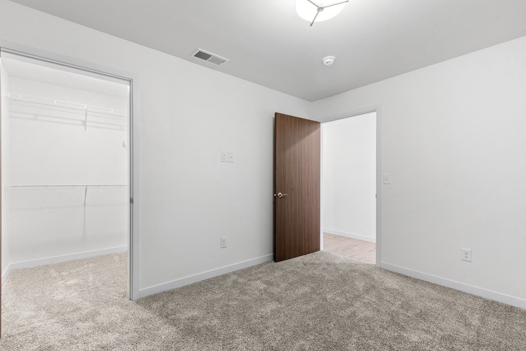 an empty bedroom with white walls and a door to a closet