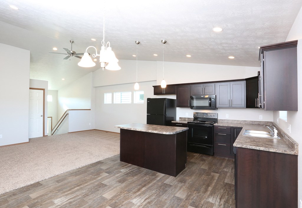 an open kitchen and living room with dark wood cabinets and white walls
