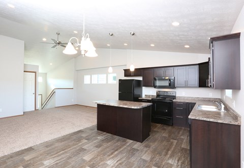 an open kitchen and living room with dark wood cabinets and white walls