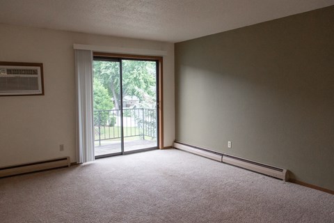 an empty living room with a sliding glass door to a balcony