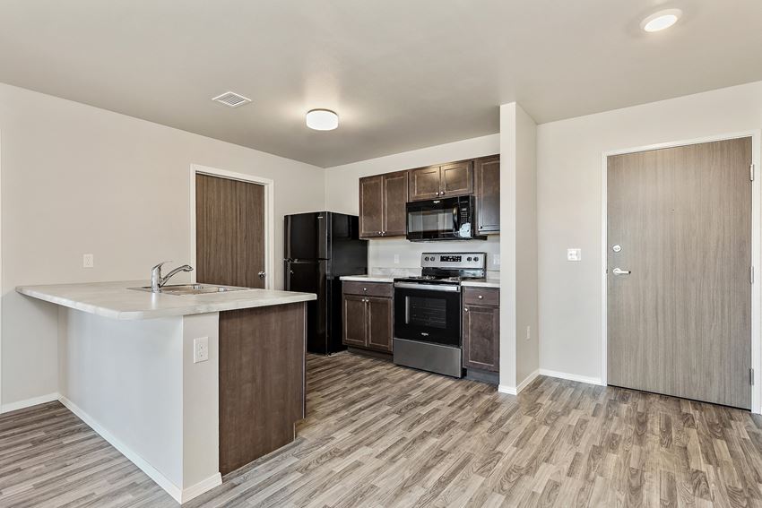 a kitchen with a white counter top and a black refrigerator