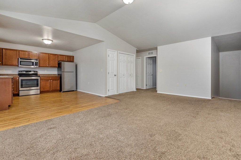 A spacious living room with a kitchen area in the background.