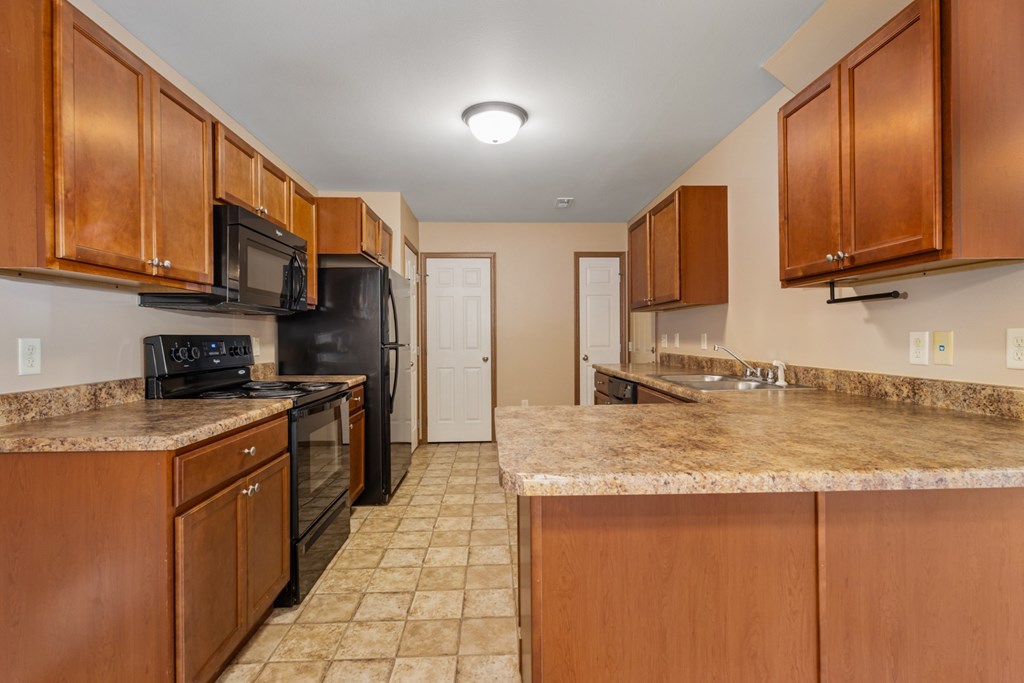 A kitchen with brown cabinets and granite countertops.