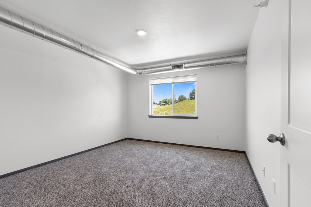A room with a window showing a blue sky and greenery outside.