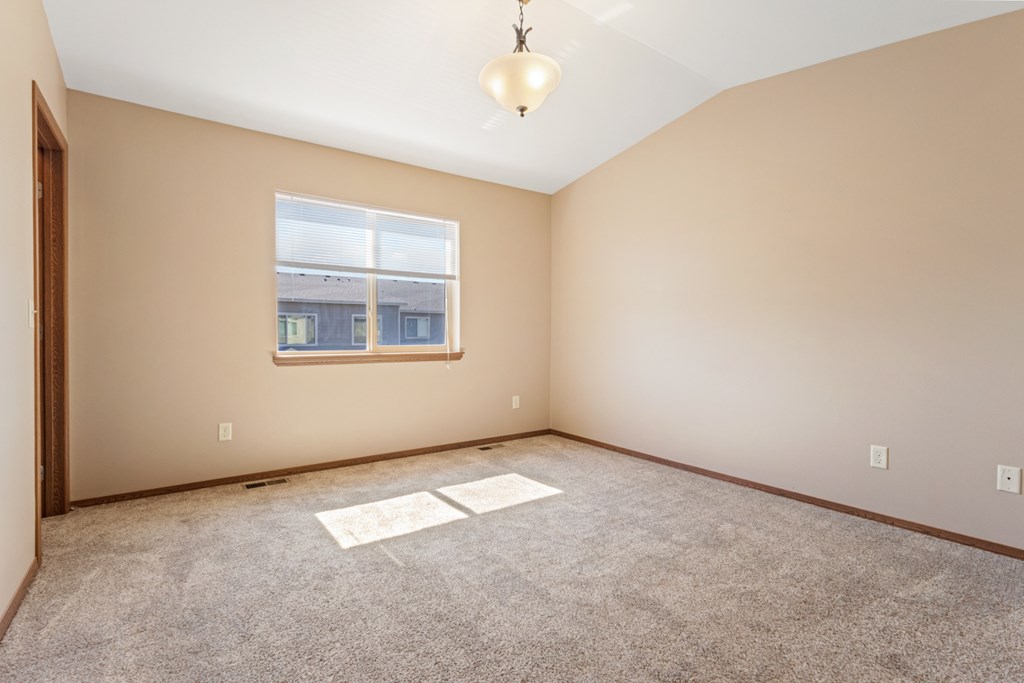 A room with a window and a carpeted floor.