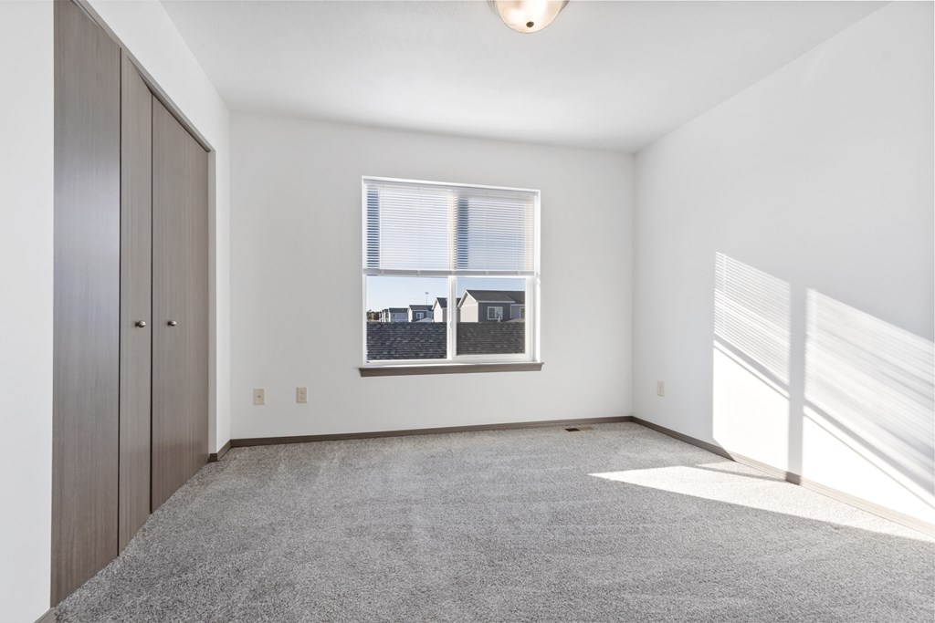 A room with a window and a grey carpet.