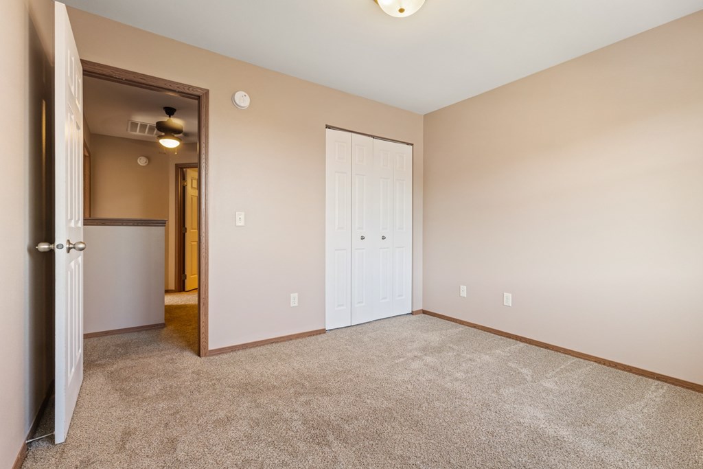 A room with a carpeted floor and two doors.