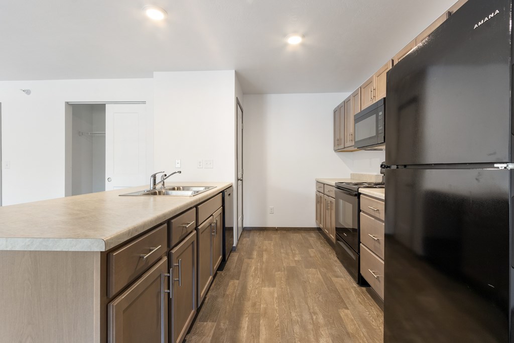 A kitchen with wooden floors and a black refrigerator.