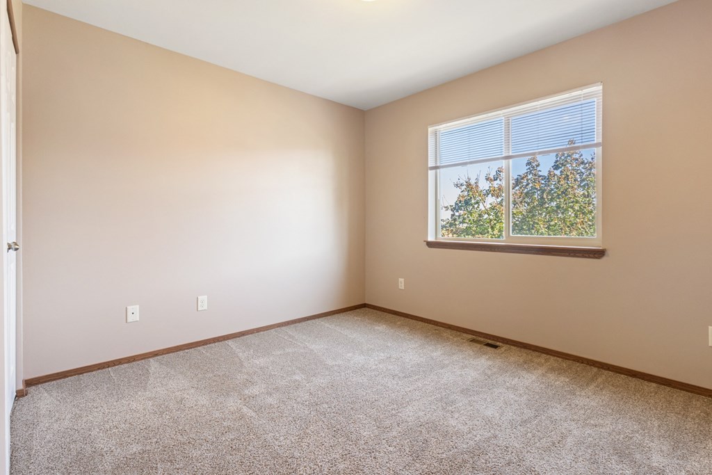 A room with a window showing trees outside.