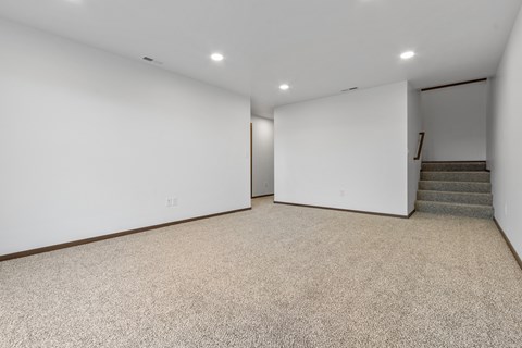 A spacious room with a staircase leading to another room.